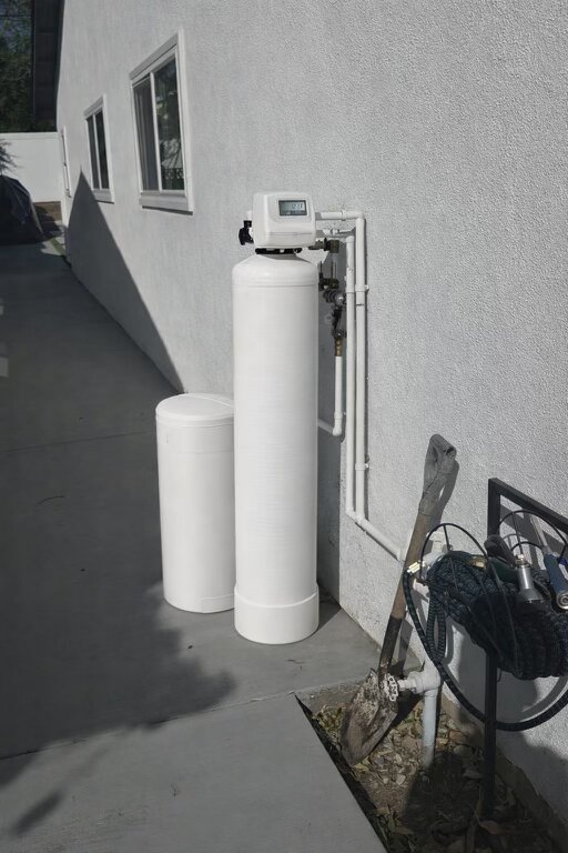 White water softener and brine tank installed outside home