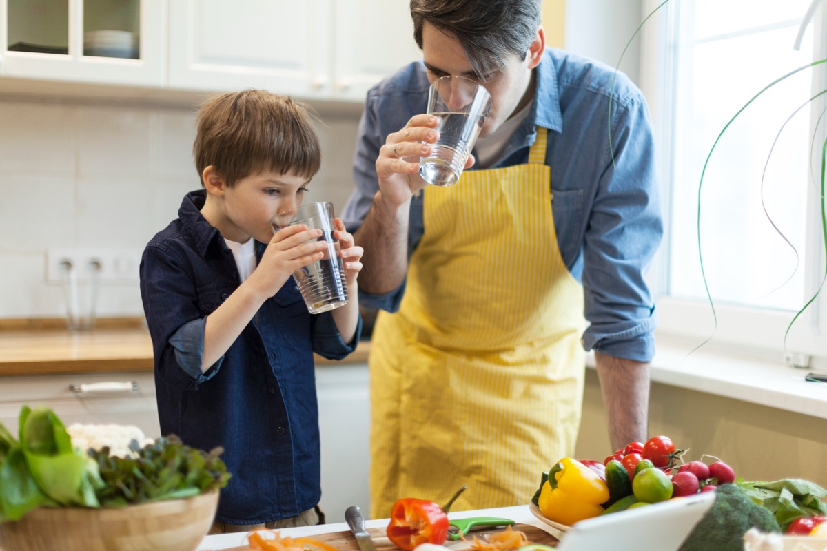 Father and son drinking clean water in kitchen